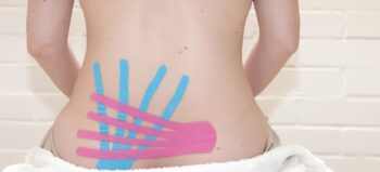 blaue und rosa Kinesiotapes auf einem Frauenrücken.