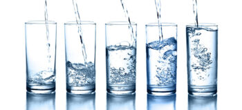 Fünf Gläser unterschiedlich hoch mit Wasser gefüllt.