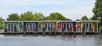 Fünf Hausboote in bunten Farben, am Ufer.