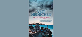 Cover mit Aufschrift „Veit Heinichen. Die Zeitungsfrau. Commissario Laurenti in schlechter Gesellschaft“. Im Vordergrund eine Hafenmole mit dicken, alten Tauen, auf der anderen Seite des Hafenbeckens Blick auf das alte Triest. Der Himmel ist mit dunklen Wolken verhangen.