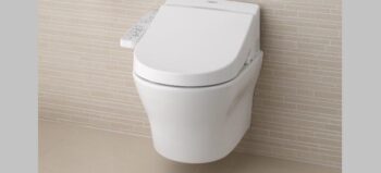Weiße Toilette mit Bedienelementen auf einer Wand mit beigen Fliesen.