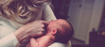 Baby in den Armen einer blonden Frau.