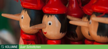 Mehrere Köpfe von Pinocchio-Figuren aus Holz mit schwarzen Haaren, roter Kappe, rotem Oberteil und langer Nase.