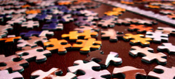Bunte Puzzleteile auf braunem Untergrund.