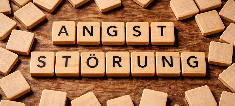Hölzerne, quadratische Scrabble Klötzchen, aus denen das Wort Angststörung gelegt ist.