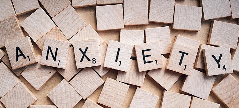 Hölzerne, quadratische Scrabbleklötzchen, die das Wort Anxiety (dt.: Angst, Angstzustand) legen.