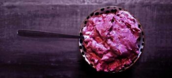 Violette Beeren Nice Cream in einer Schüssel; darin ein langer Löffel.